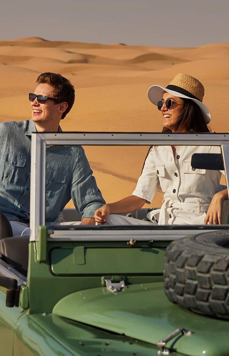 A couple enjoying a desert safari from the back seat of an off-roader.