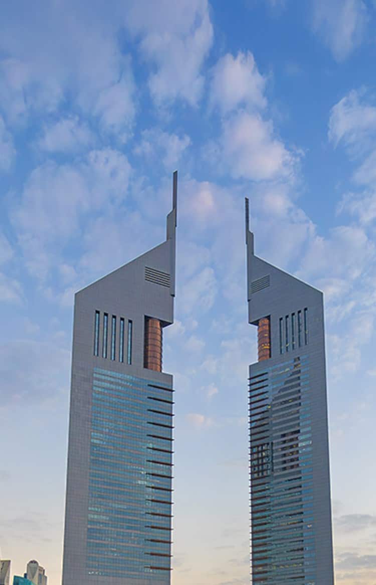 Emirates Towers rising above Dubai's business district under a cloudy sky