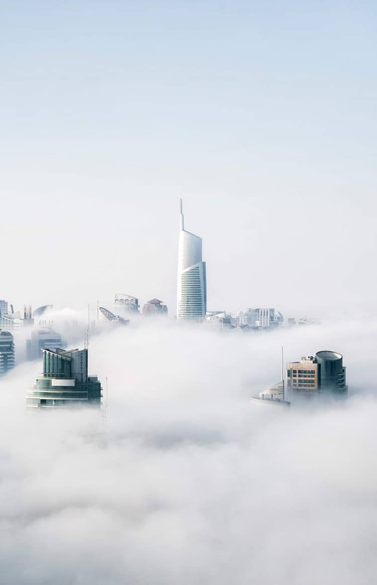 Aerial view of skyscrapers sticking out of a blanket of clouds.