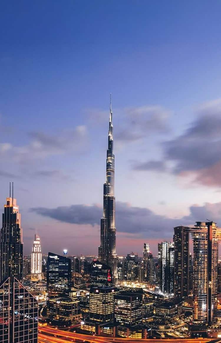 Dubai skyline at sunset featuring the Burj Khalifa surrounded by illuminated skyscrapers