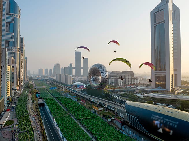 Aerial view of thousands of runners filling Sheikh Zayed Road, with paramotors flying above near the Museum of the Future