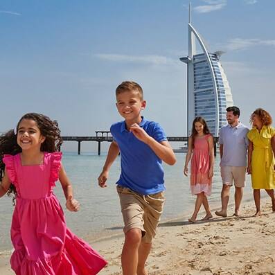 Family running on a beach in front of Burj Al Arab