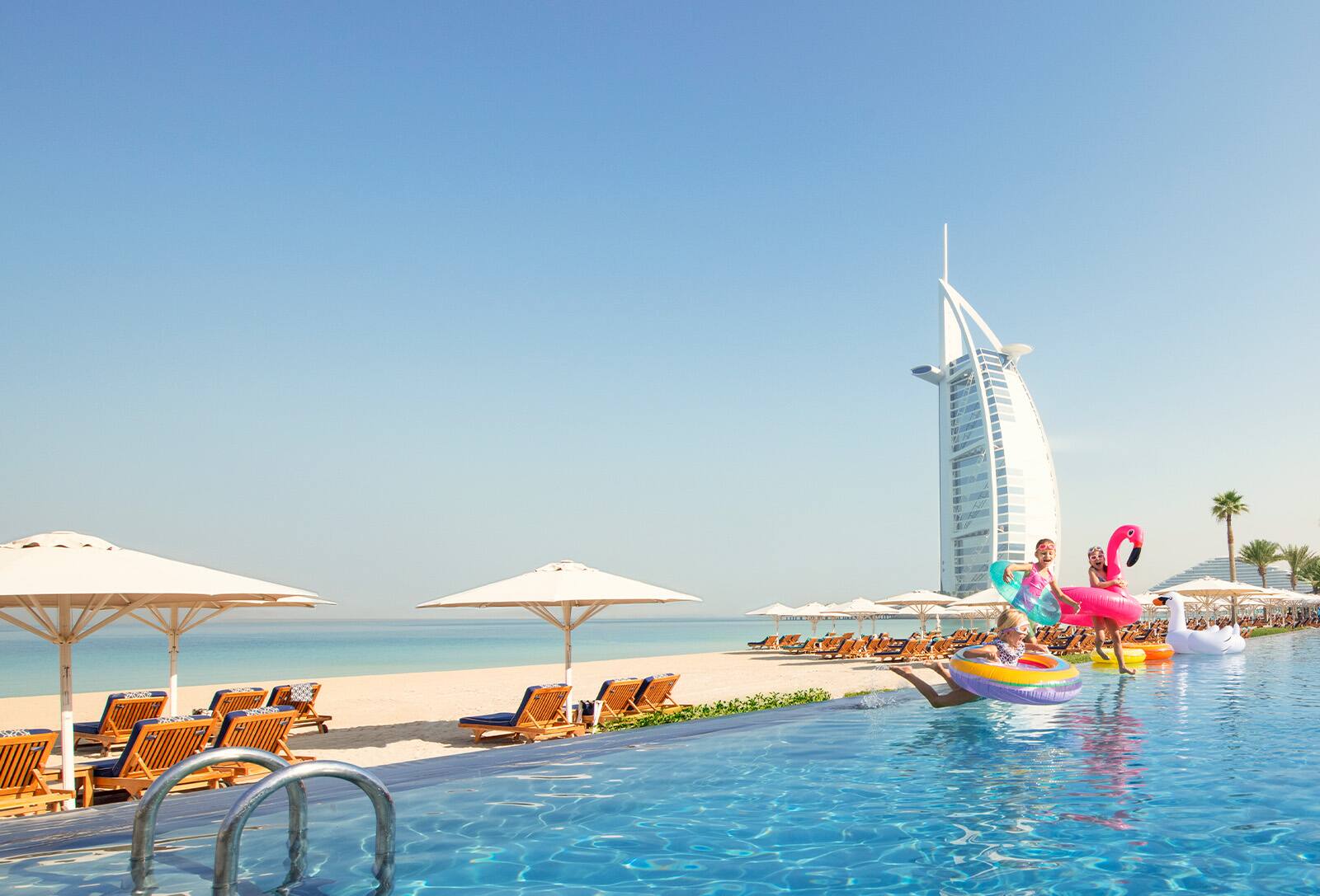Kids playing in a pool in front of Burj Al Arab in Dubai
